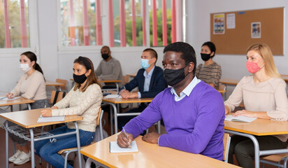 African-american student wearing protective mask among students in university classroom
