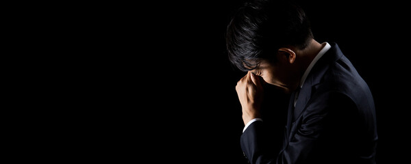 黒背景で悩んでいる男性ビジネスマン