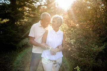 Senior couple in love and very happy enjoying a walk in the field at sunset