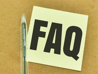 Text FAQ written on yellow paper note with pen.Business concept.