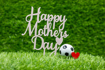 Soccer ball for Mother's Day on green grass with red heart love mom from Soccer