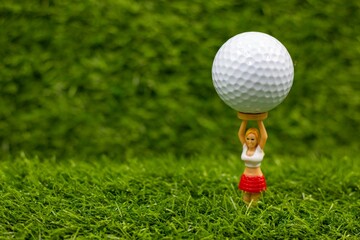Golf ball is on caddy tee on green grass background