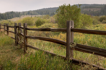 Fototapeta na wymiar Old fence in Colorado overlooking a pasture of grass and trees