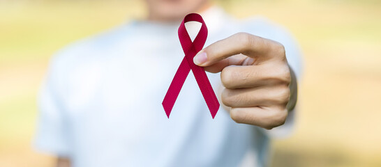 Burgundy Red Ribbon for supporting people living and illness. Healthcare and safe sex concept....