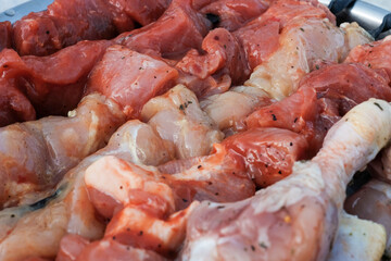 Raw pork skewers and chicken thighs cut into pieces and on skewers closeup