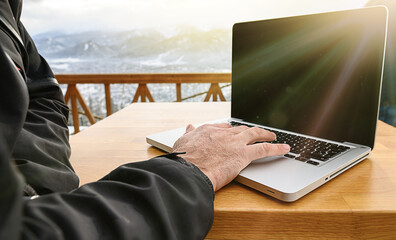 Side view of a male hands mountain climber using laptop on mountain peak