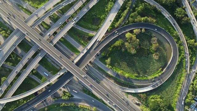 4K. Aerial view of road interchange or highway intersection with busy urban traffic speeding on the road. Junction network of transportation taken by drone.