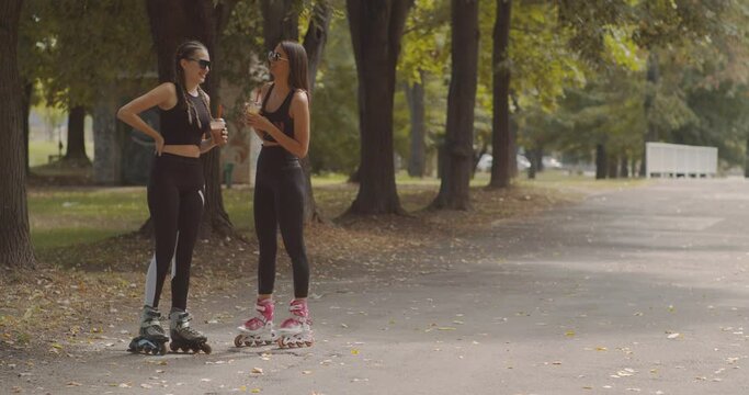 Two girls rollerskating in the park