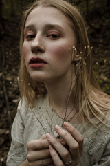 Portrait of a beautiful mysterious woman with blond hair in the forest. like a fairytale. Warm tone	
