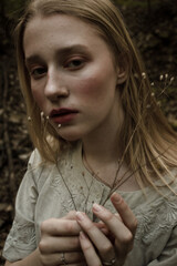 Portrait of a beautiful mysterious woman with blond hair in the forest. like a fairytale. Warm tone	
