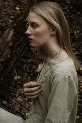 Portrait of a beautiful mysterious woman with blond hair in the forest. like a fairytale. Warm tone	
