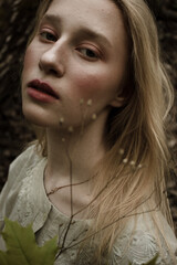 Portrait of a beautiful mysterious woman with blond hair in the forest. like a fairytale. Warm tone	
