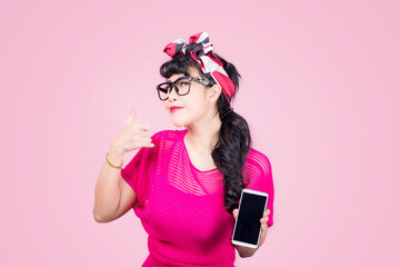 Call me. Asian young woman cute smiling mobile phone showing call me sign hand gesture ,retro vintage 50s hairstyle isolated on pink background