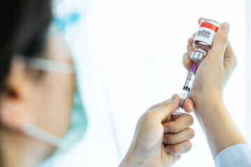 Doctor pulling a vaccine from vaccine does into syringe.