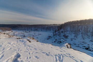 Winter landscape with frozen river, snow, rocks and trees