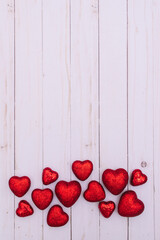 A bunch of red glittery hearts on white rustic wooden background. Valentine's day backdrop. Cool and trendy cute whiteboard image for celebration.