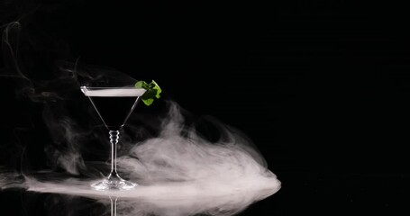 Glass of martini and smoke on black background