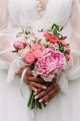 wedding bouquet of white and pink roses and peonies in the hands of the bride