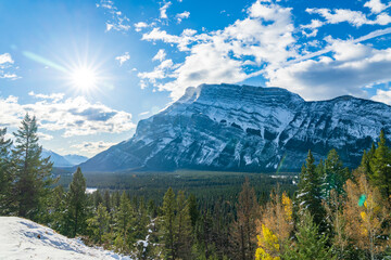 Banff National Park beautiful landscape. Mount Rundle mountain valley with green and yellow color trees forest in snowy autumn sunny day. Canadian Rockies.