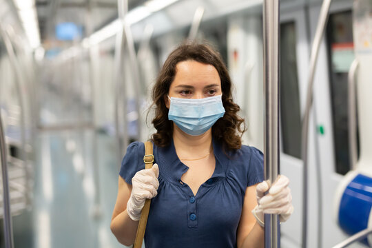 Portrait Of Focused Woman In Disposable Mask And Gloves Traveling In Subway Train During Daily Commute To Work In Spring Day. Concept Of New Life Reality And Precautions In COVID 19 Pandemic