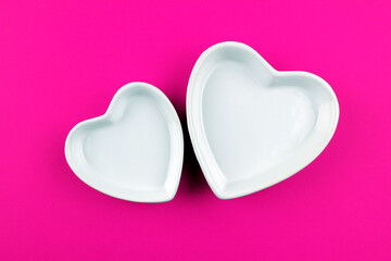 Two heart shaped plates on pink background