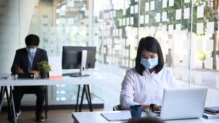 Businesspeople or office worker wearing protective mask and working together in office.