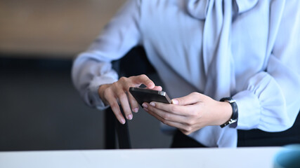Cropped shot of businesswoman sitting at her office desk and using mobile phone.