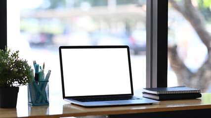 Mockup image of computer laptop, notebook, stationery and plant on white table. White empty screen for advertise text.