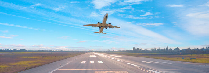 White Passenger plane fly up over take-off runway from airport 