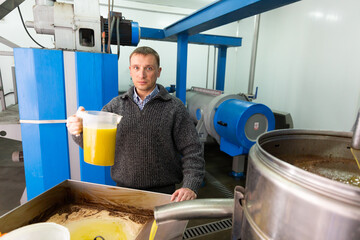 Man engaged in traditional olive oil production, controlling process of oil decanting