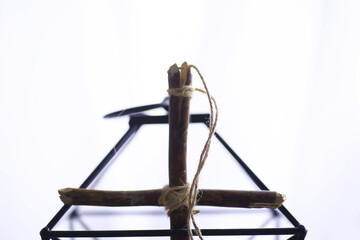 Obraz premium Religious concept. Handmade wooden cross on a white background. Wine glass lamp with candles.