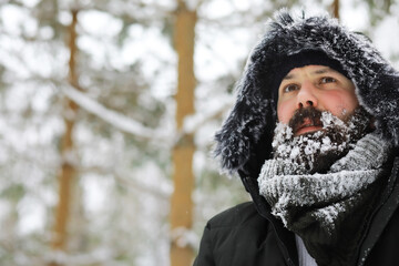 Bearded man in the winter woods. Attractive happy young man with beard walk in the park.