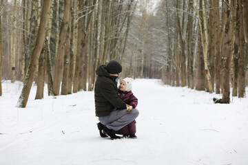 Fototapeta premium Happy family playing and laughing in winter outdoors in the snow. City park winter day.