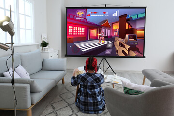 Young woman playing video games on big screen at home