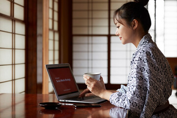 旅館でワーケーションする浴衣姿の若い女性