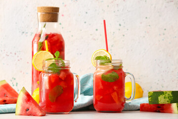 Bottle and mason jars of tasty cold watermelon lemonade on table