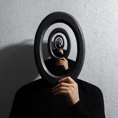 Rätselhafte surrealistische optische Täuschung, junger Mann mit rundem Rahmen auf strukturiertem grauem Hintergrund. © Lalandrew