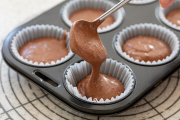 自宅でお菓子作り　チョコレートマフィン生地を型に注ぐ様子