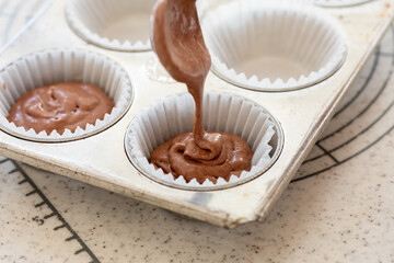 自宅でお菓子作り　チョコレートマフィン生地を型に注ぐ様子