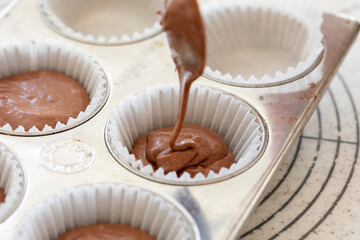 自宅でお菓子作り　チョコレートマフィン生地を型に注ぐ様子