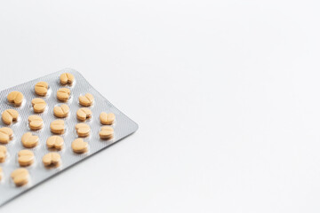 Close-up of blister with yellow pills on white background.