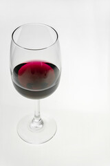 Vertical shot. A glass of red wine on a light background. 