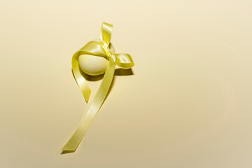 Close up of a yellow painted egg with a ribbon