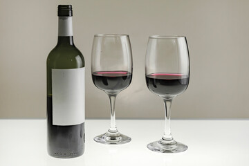 Two glasses and a bottle of red wine on a blurred homogeneous background. Horizontal photo