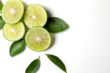 Naklejka na ściany i meble Fresh green Thai lemons, whole and sliced ​​with their leaves, placed on a isolated white background. With copy space.