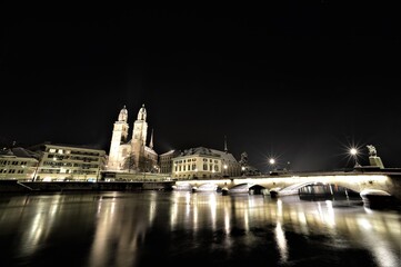 At night in snow on the Limmat with a view of Grossmünster, Münsterbrücke and Limmatquai in Zurich