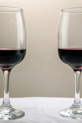 Vertical shot. Two glasses of red wine on a blurred homogeneous background. 
