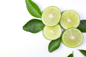 Fresh green Thai lemons, whole and sliced ​​with their leaves, placed on a isolated white background. With copy space.
