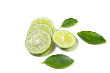Fototapeta na wymiar Fresh green Thai lemons, whole and sliced ​​with their leaves, placed on a isolated white background. With copy space.