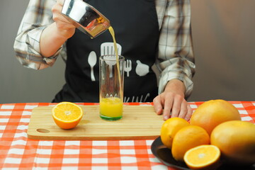 A young man pours freshly squeezed citrus juice into a